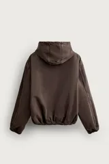 Cazadora de denim de algodón color negro con efecto lavado, de corte relaxed fit, manga larga y capucha. Cuenta con cierre frontal de cremallera, bolsillos frontales tipo canguro y acabados con elástico en puños y cintura.