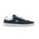 Championes Lacoste modelo Baseshot, de diseño urbano y perfil bajo. Confeccionados en gamuza color azul marino, presentan cordones blancos, suela de goma blanca y el logo del cocodrilo bordado en el lateral con la inscripción EST. 1933.