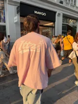 Remera rosa de corte holgado con estampado trasero de la palabra "Ittai" en blanco con una estrella.