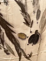 Mantel rectangular de viscosa color crema con estampado de hojas y flores en tonos marrones y dorados.