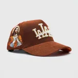 Gorra tipo trucker de pana color marrón, con bordado frontal en relieve y detalle lateral bordado del Sagrado Corazón de Jesús.