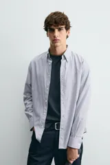 Camisa de corte regular fit confeccionada en tejido de algodón con diseño de rayas verticales. Presenta cuello abotonado, manga larga con puños abotonados y cierre frontal de botones.