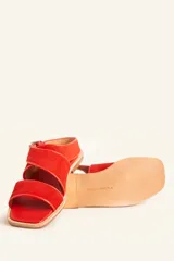 Sandalias bajas de cuero negro con tachas plateadas, tiras cruzadas y hebilla al tobillo.