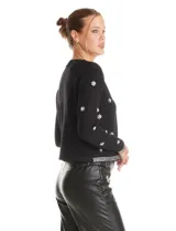 Chaqueta tejida de punto color negro, con cuello redondo y cierre frontal invisible. Presenta un diseño decorado con apliques de strass facetados y perlas en forma de flores y líneas en los bordes.