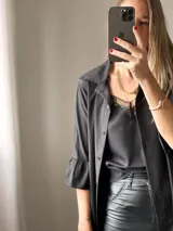 Camisa negra de tejido suave tipo seda, con manga tres cuartos y volados irregulares en mangas y ruedo.
