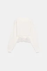 Sudadera crop de cuello redondo y manga larga con puños elásticos. Presenta un diseño de doble capa con bajo acabado en encaje a tono.