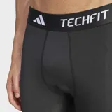 Calza deportiva de compresión Adidas Techfit, color negro, con cintura elástica que lleva la inscripción "TECHFIT" en blanco. Presenta las tres franjas características de Adidas en blanco a lo largo de las piernas.