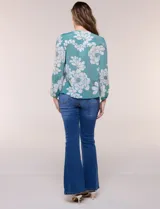 Blusa de gasa texturizada color verde con estampado floral blanco, cuello mao con escote en V y botones frontales. Cuenta con mangas 3/4 abullonadas y detalles de puntilla calada en el pecho.