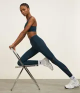 Legging deportiva de tiro alto en color azul oscuro, confeccionada en microfibra de poliamida y elastano. Presenta recortes laterales en tela de malla para mayor transpirabilidad y un ajuste ceñido al cuerpo, ideal para actividades de alta intensidad.