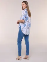 Camisa de lino sintético con estampado floral en tonos azules y beige sobre fondo blanco, de corte holgado, mangas tres cuartos y cuello camisero.