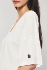 Remera oversize color blanco, confeccionada en jersey Pima flamé de algodón. Cuenta con escote en V, mangas cortas con detalle de bordado en la manga y cintura con elástico que genera un efecto balloon.