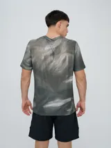 Remera deportiva Umbro modelo Niso, de manga corta y cuello redondo, con estampado abstracto en tonos negro y gris, y logo de la marca impreso en el pecho.