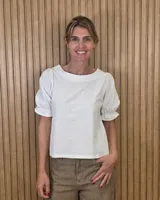 Blusa de lino color blanco, con escote redondo a la base y mangas cortas abullonadas con terminación fruncida.