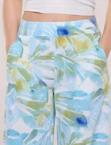 Pantalón crop de lino y rayón, con diseño wide leg de corte holgado, estampado tropical de hojas en tonos verde, azul y marrón sobre fondo blanco. Cuenta con pretina trasera elastizada y bolsillos delanteros.