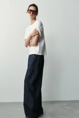 Camiseta blanca de algodón con cuello redondo y manga corta, con detalle de aplicaciones de flores en relieve en los dobladillos de las mangas.