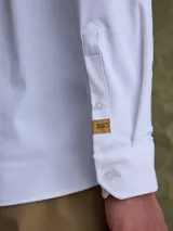 Camisa de manga larga color azul marino, con cuello clásico, cierre frontal de botones y un bolsillo en el pecho.