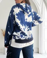 Buzo con capucha color azul y blanco con estampado tie-dye, de corte holgado y mangas largas.