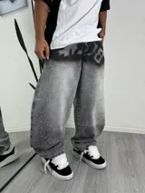 Pantalón de jean corte baggy, color gris lavado con efecto desgastado, decorado con pequeños cristales tipo strass dispersos y estampado artístico en la zona de la cintura.