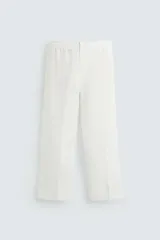 Pantalón de corte relajado confeccionado en tejido de lino. Presenta cintura elástica, bolsillos frontales, bolsillo trasero de vivo y cierre frontal con cremallera y botón.