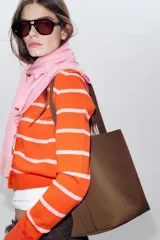 Bolso de hombro tipo saca, de diseño minimalista y estructura flexible, con asa única y cierre mediante clip metálico.