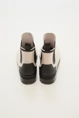 Botas de lluvia bajas color beige con elástico lateral negro y suela de goma negra.