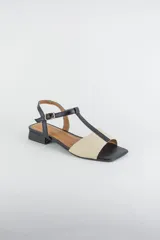 Sandalias de cuero combinadas en negro y marfil, con diseño de tiras en T, taco cuadrado bajo y pulsera con hebilla ajustable al tobillo.