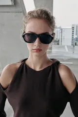 Jersey de punto color marrón oscuro, con cuello redondo y manga larga. Presenta un diseño con aberturas y nudos decorativos en los hombros.