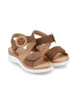 Sandalia de cuero nobuck color marrón chocolate, con tira frontal ajustable con velcro, tira trasera con hebilla decorativa redonda forrada en yute y suela con detalle de yute y base blanca de goma.