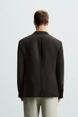 Blazer regular fit color marrón oscuro confeccionado en tejido de lino. Tiene cuello con solapas de muesca, manga larga con puño abotonado, bolsillo de vivo en el pecho, bolsillos de solapa en la cadera, bolsillo interior, bajo con aberturas en la espalda y cierre frontal con botonadura.
