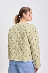 Cazadora capitoneada de corte recto, con diseño de rayas verticales verdes y estampado floral. Presenta cuello redondo, cierre frontal con botones y bolsillos laterales de parche.