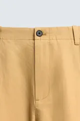 Pantalón chino straight fit de corte recto y holgado, color tostado, con pliegues frontales en la cintura, bolsillos laterales y cierre con cremallera y botón.