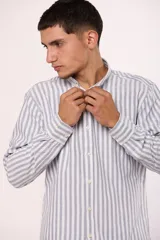 Camisa de manga larga con estampado de rayas verticales, cuello abotonado y cierre frontal con botones.