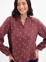 Blusa de algodón color bordó con estampado de lunares claros, cuello mao, cierre frontal con botones y mangas largas.