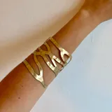 Brazalete dorado con diseño calado y forma irregular.