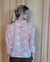 Blusa de algodón color azul, de corte suelto, con mangas largas abullonadas y cuello con volados y escote en V.