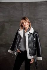 Campera tipo gamulán de cuero sintético negro con interior y solapas de corderito sintético en color blanco. Presenta cierre frontal, bolsillos laterales con cierre y cinturón ajustable en la cintura.