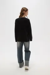 Sweater de punto jacquard con diseño floral abstracto en tonos tierra sobre fondo negro, de corte holgado, cuello redondo y manga larga.