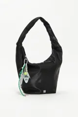 Bolso tipo hobo de color negro con acabado satinado y estructura blanda. Cuenta con un asa corta integrada, cierre superior y un llavero decorativo con temática de tenis colgando del tirador del cierre.