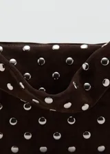 Bolso de hombro tipo baguette confeccionado en piel bovina color marrón oscuro, con diseño estructurado y superficie decorada con tachas metálicas plateadas distribuidas uniformemente. Cuenta con cierre superior y asa integrada.