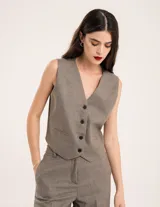 Chaleco de vestir gris oscuro con textura tipo tweed, escote en V y botones frontales. Corte levemente entallado y largo a la cintura.
