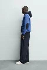 Sudadera hoodie regular fit de color azul, con capucha y bolsillo canguro negro. Cuenta con cordones ajustables blancos y detalles en color negro en la capucha, el bolsillo y los puños.