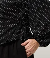 Blusa de crepé con estampado de lunares, diseño cruzado con escote en V, mangas largas con puños elásticos y lazo lateral ajustable. Incluye forro interno.