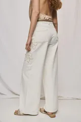 Jean wide leg blanco de tiro medio, con calce amplio y detalle de flores bordadas en los laterales.