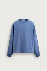 Sudadera azul con corte relaxed fit, cuello redondo y mangas largas con puños de rib, confeccionada en tejido con mezcla de algodón y acabado afelpado en el interior.