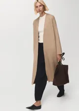 Abrigo largo de tejido de punto en color beige, con diseño recto, cuello solapa y manga larga. Presenta un corte abierto sin cierre frontal.