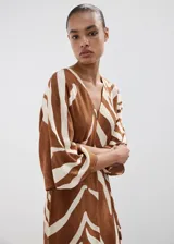 Vestido midi con estampado animal print tipo cebra en tonos marrón y blanco, de corte recto, con escote en V, mangas tres cuartos y tajo delantero en la falda. Incluye un cinturón fino ajustable.