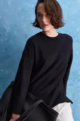 Sweater blanco de punto con diseño holgado, cuello redondo, mangas largas acampanadas y detalles de textura horizontal en el tejido.