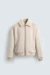 Cazadora regular fit de tejido efecto ante en color beige, con interior de borreguillo a tono, cuello solapa, cierre frontal de cremallera, bolsillos de vivo y acabados en rib en puños y bajo.