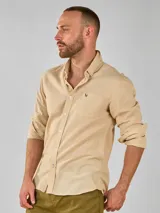 Camisa de lino color beige, de manga larga con puños abotonados y cuello abotonado.