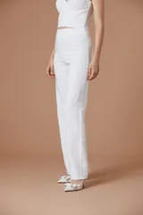 Pantalón de mujer blanco de corte sastrero, tiro alto y silueta amplia de pernera recta con detalles de flecos o pedrería en los laterales.